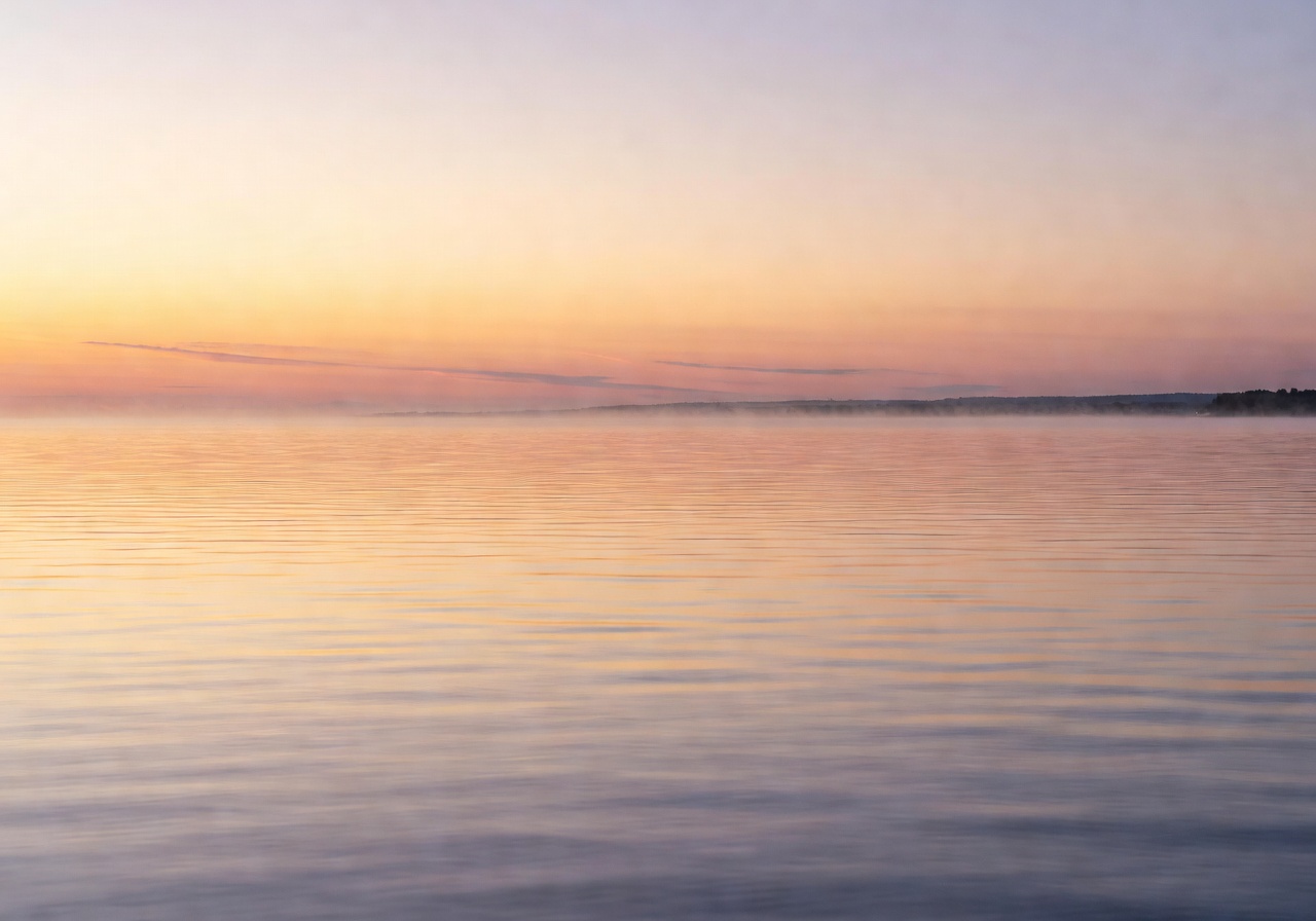 Sunrise over the calm Baltic Sea with soft golden and pink light reflecting on gentle waves near the Latvian coast